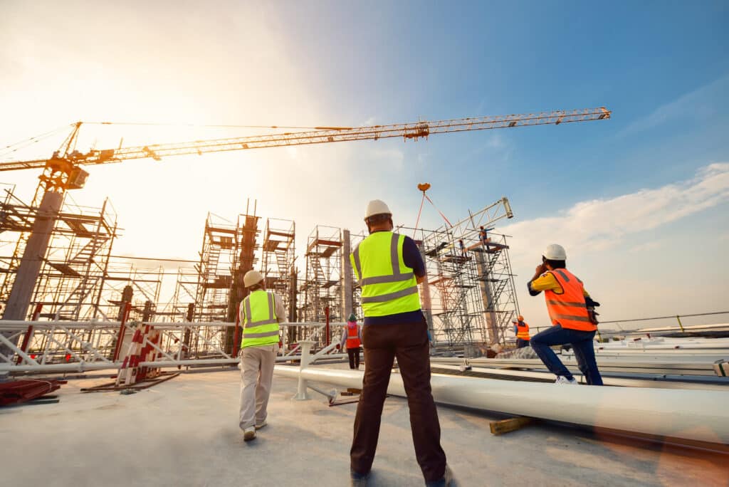 Bauarbeiter mit Warnwesten und Helmen auf einer Baustelle mit Kränen